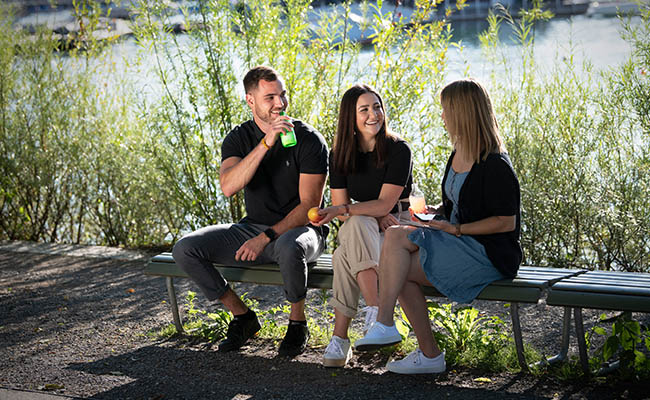 Tre collaboratori di Helsana fanno una pausa pranzo insieme nella natura (Foto)